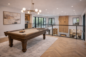 Luxury second-floor game room overlooking the main living area with open railing and modern design — by Infinit Interiors