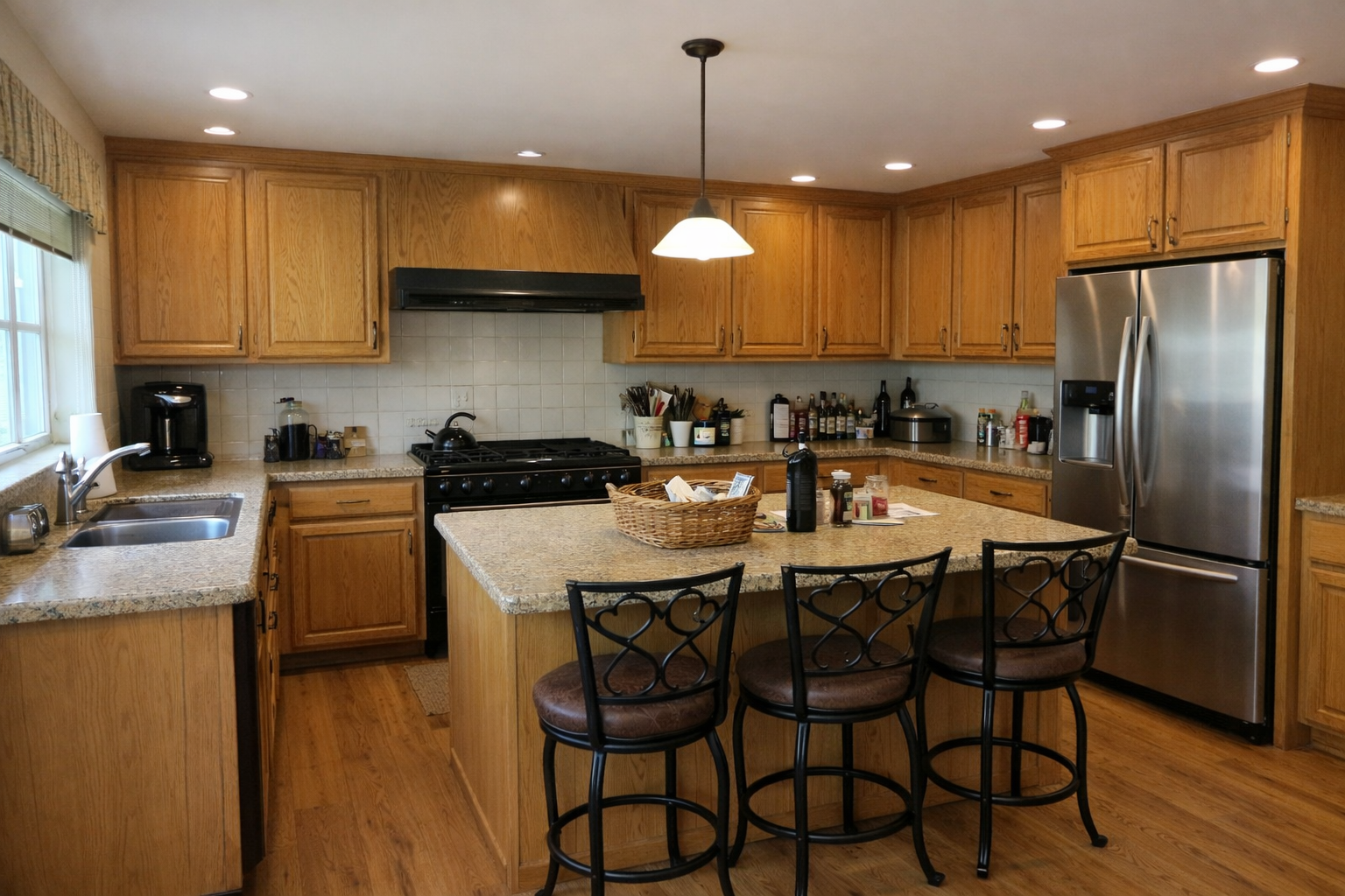 Dated oak cabinet kitchen with granite island and black appliances before renovation in Houston — by Infinit Interiors