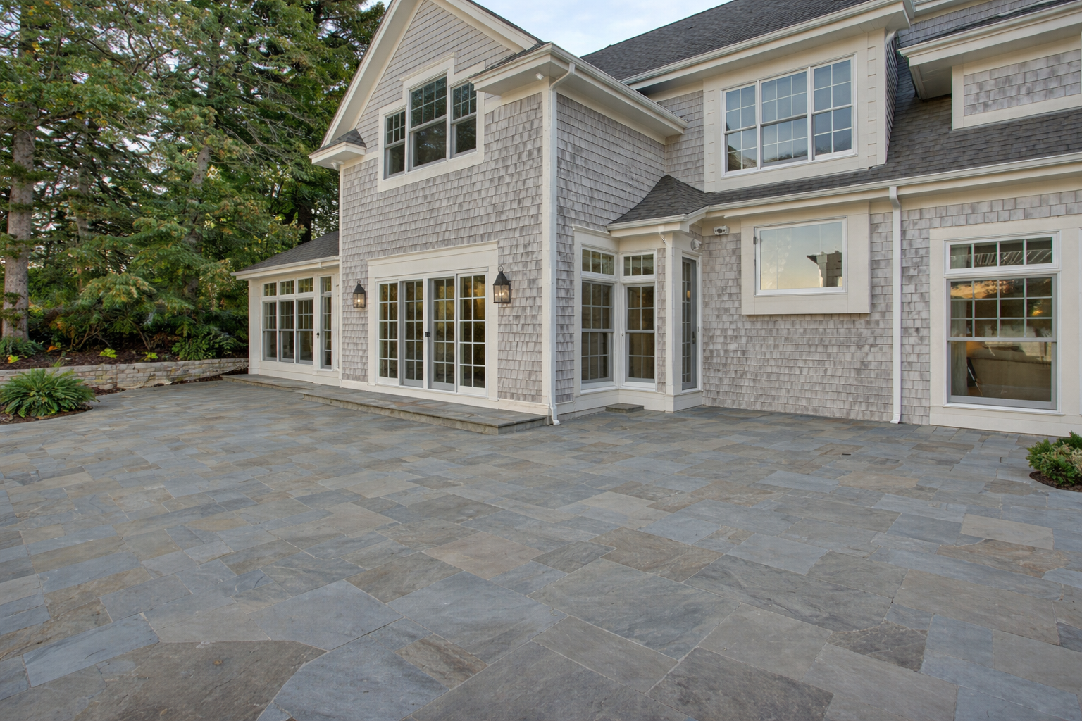 Spacious bluestone patio and rear elevation of a luxury Lake Travis home in Austin, Texas, ready for outdoor kitchen construction — by Infinit Interiors